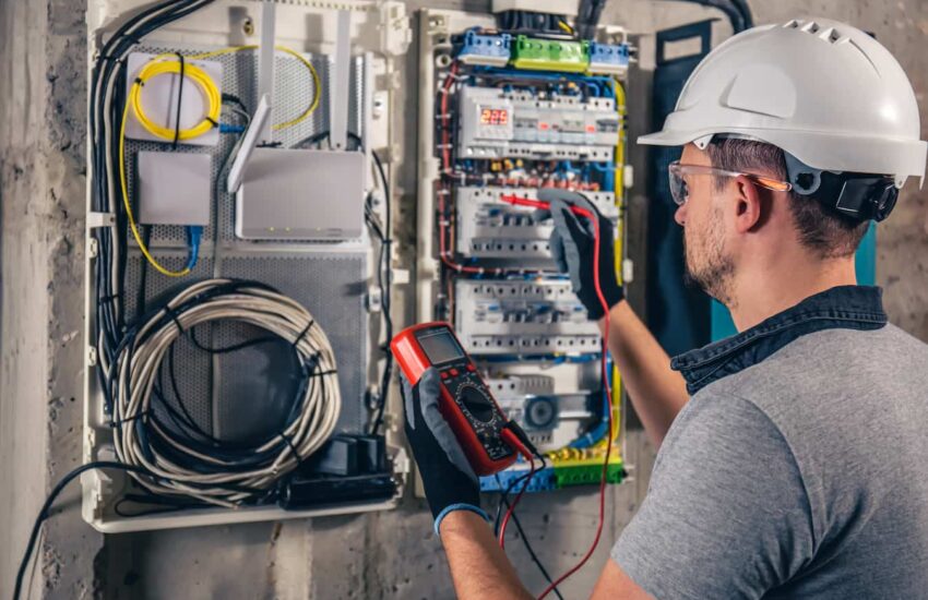 HOMME AVEC CASQUE ET GANT PRENANT MESURES DANS UN TABLEAU ELECTRIQUE 2